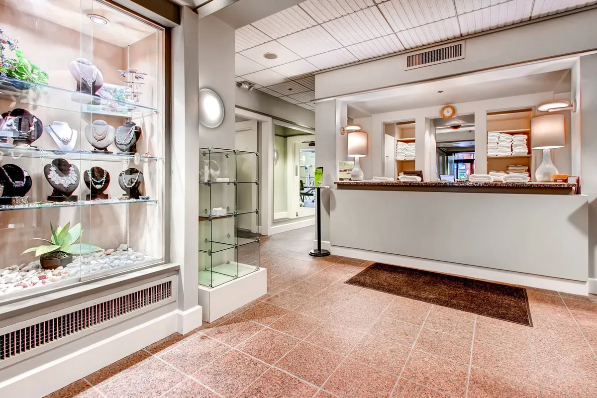A calm spa reception area with jewelry displays, a welcoming desk, and neatly arranged towels, radiating an atmosphere of tranquility and luxury. The space hints at premium spa experiences and personalized service, aligning with the mention of exclusive spa perks.