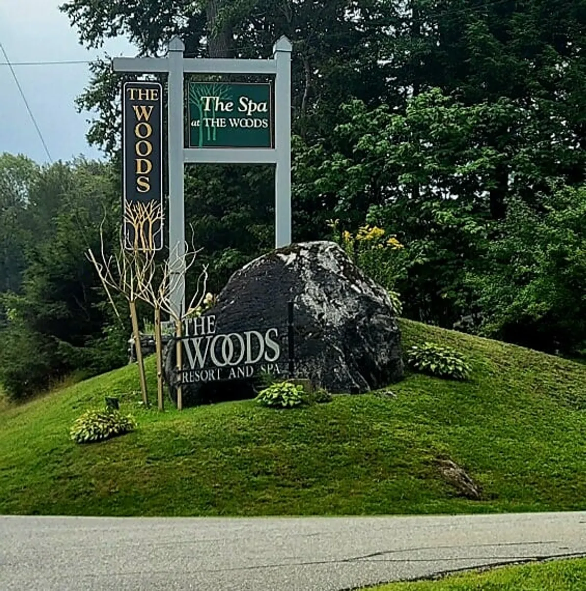 This image captures the welcoming signage for The Woods Resort and Spa, nestled among natural rock features and lush greenery. The tranquil, landscaped setting immediately evokes a sense of arrival at a peaceful retreat dedicated to relaxation and wellness.
