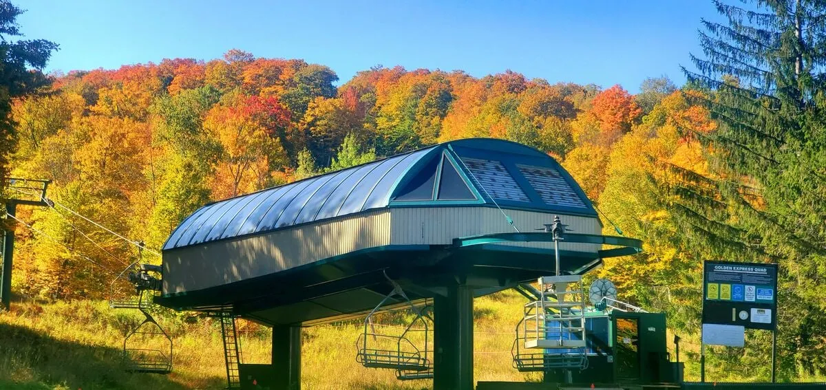 This exterior image features a ski lift station surrounded by vibrant autumn foliage. The scene captures the essence of four-season adventure, with the ski lift ready for winter sports and the colorful landscape highlighting hiking or scenic viewing opportunities in warmer months.
